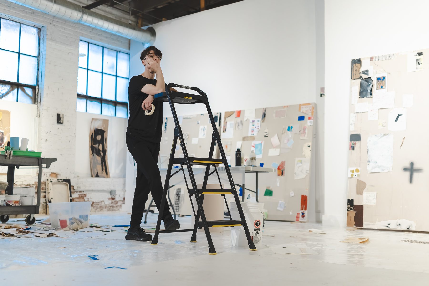 An artist in the Building 4 studio, with large steel-sash windows and work in progress on the walls