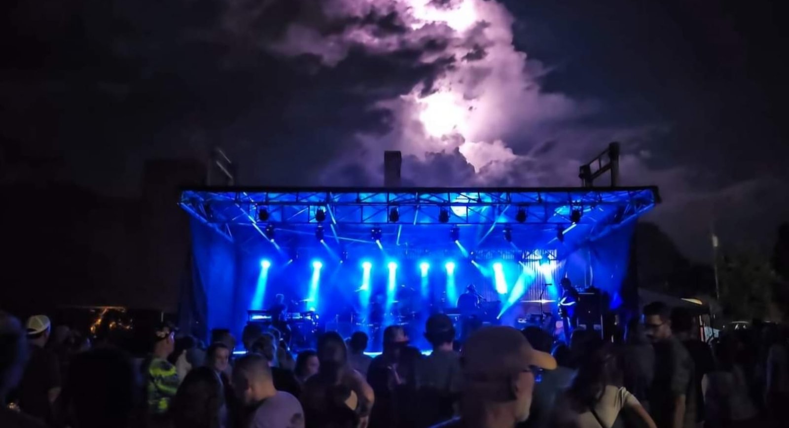Courtyard stage lit blue at night under a storm cloud