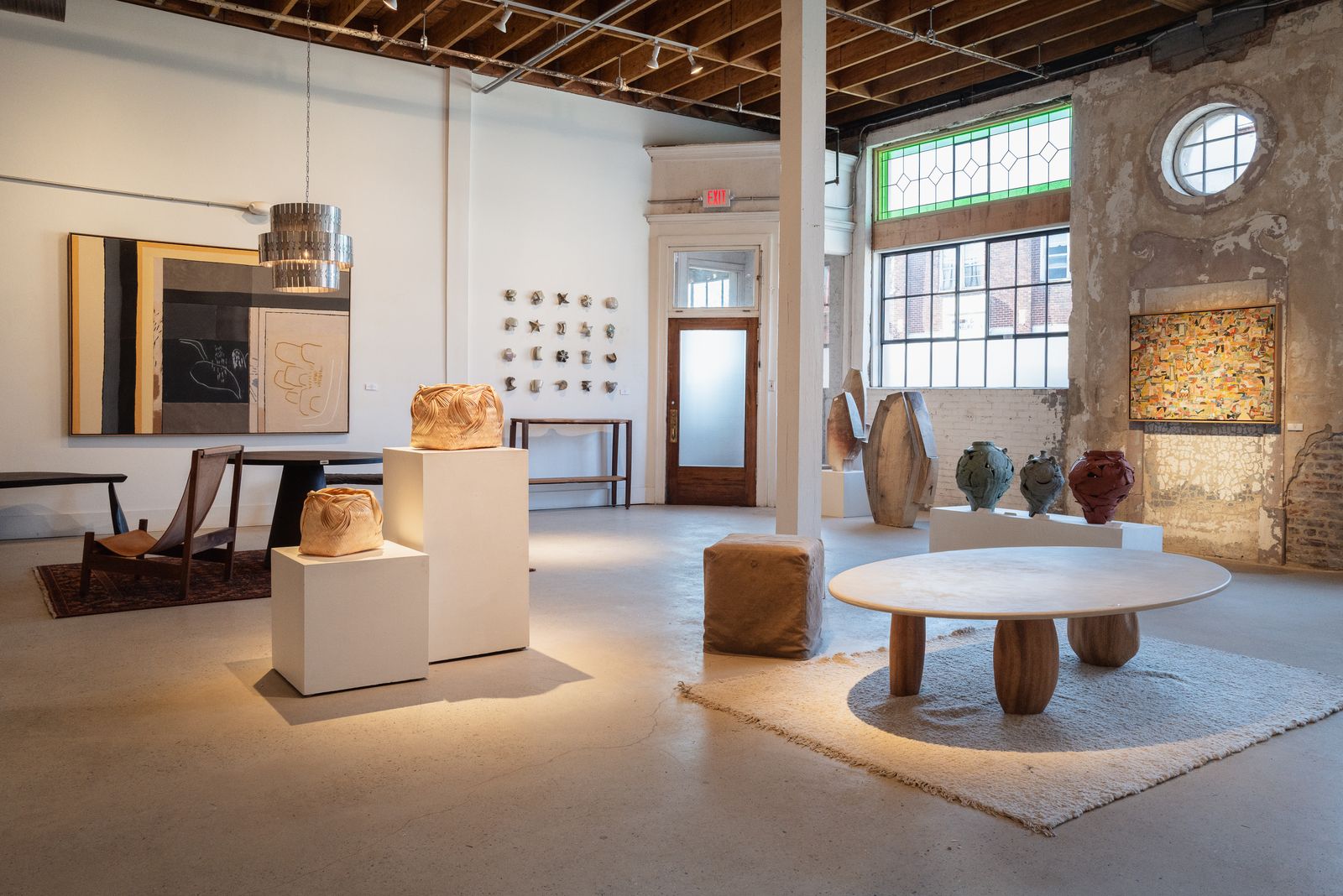 1C gallery, with a round window, exposed brick and sculpture