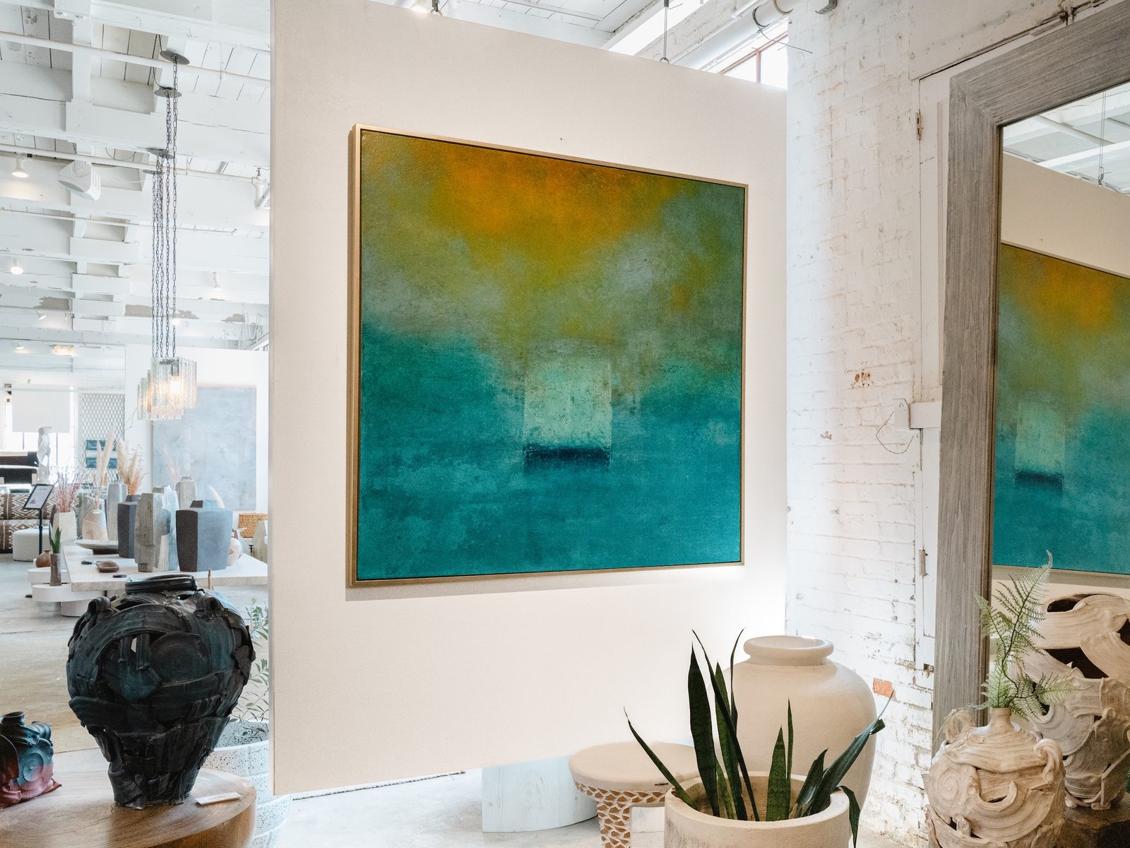 A large blue-green abstract painting shown in the mill with studio ceramics