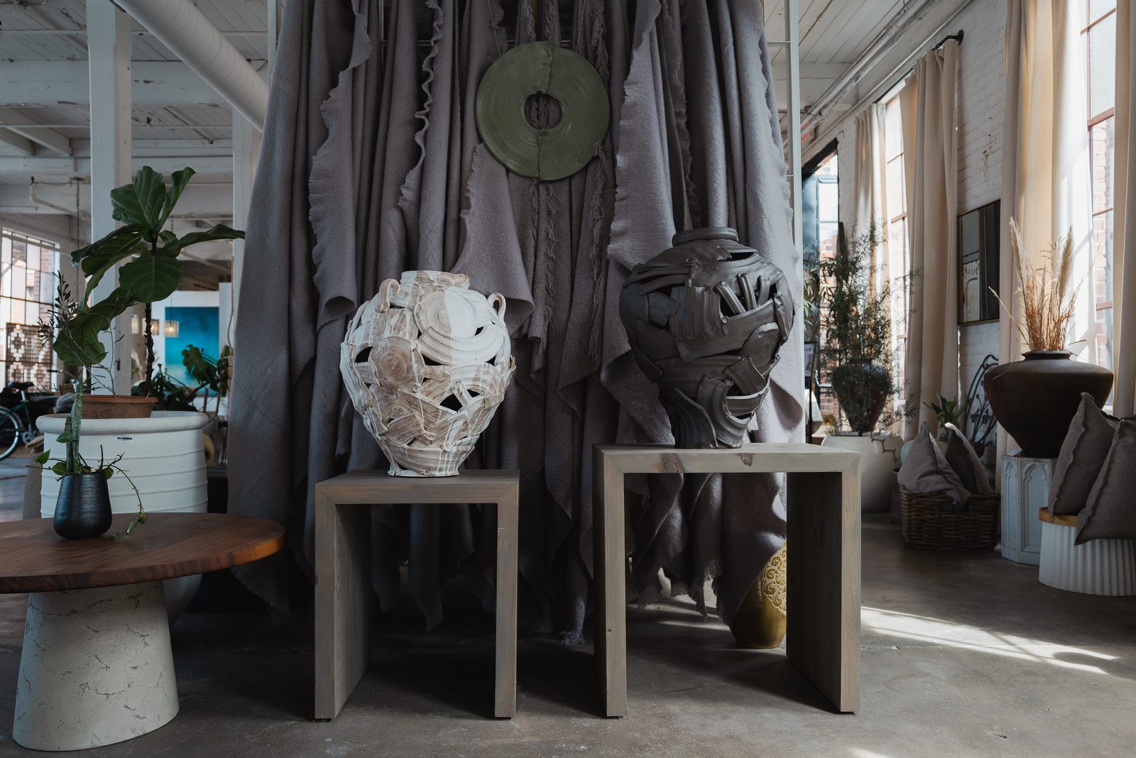 Sculptural ceramic vessels on wooden plinths in a showroom setting