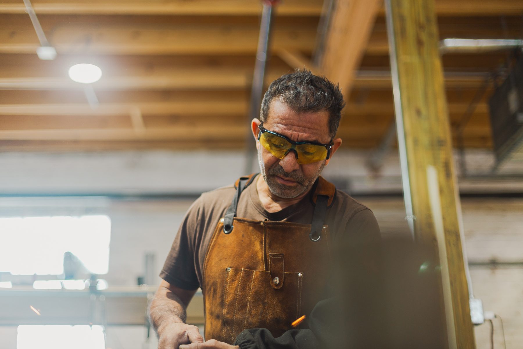 A metalworker at the bench in the 1A metal workshop, under a timber ceiling